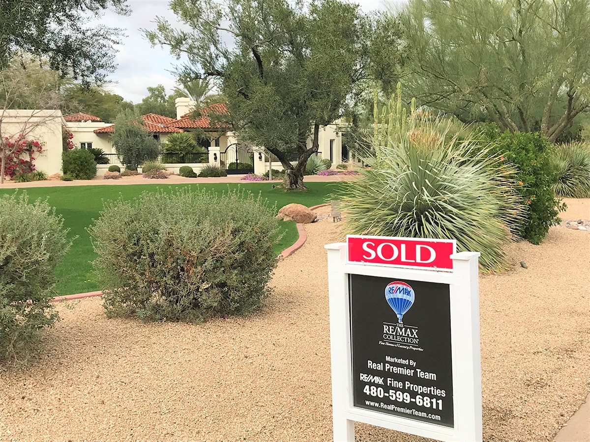 Real Premier Team's RE/MAX Collection 'Sold' sign in front of a home that exemplifies a successful sale, showcasing a ready, willing, and able buyer's dream - a gated, landscaped property